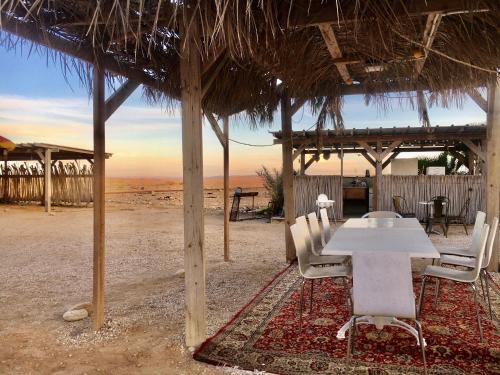 ‘EzuzにあるTobiana Desert Lodging Negevのビーチ小屋の下にテーブルと椅子