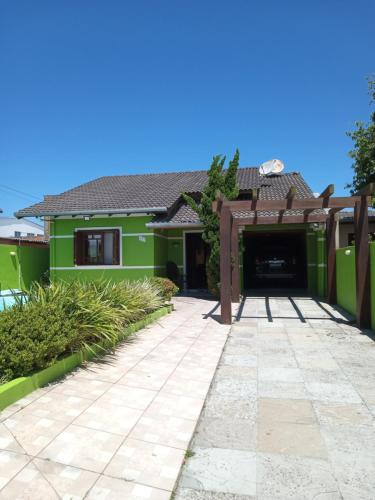 uma casa verde com uma entrada em Casa com piscina no imbé em Imbé
