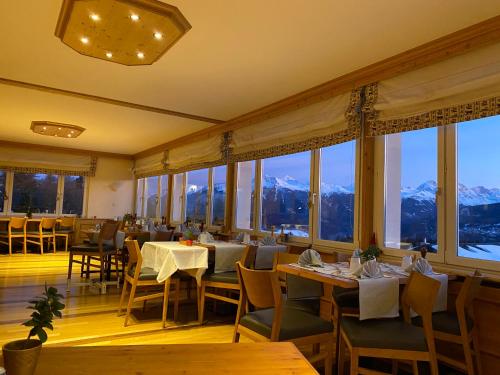ein Restaurant mit Tischen, Stühlen und Fenstern in der Unterkunft Hotel Ad'Eldorado in Crans-Montana