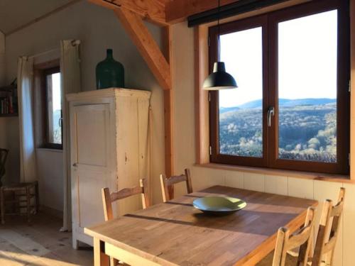 uma sala de jantar com uma mesa de madeira com cadeiras e janelas em Chalet Au bois du Haut Folin em Saint-Prix
