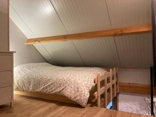 a bed in a room with a ceiling at Chalet Au bois du Haut Folin in Saint-Prix