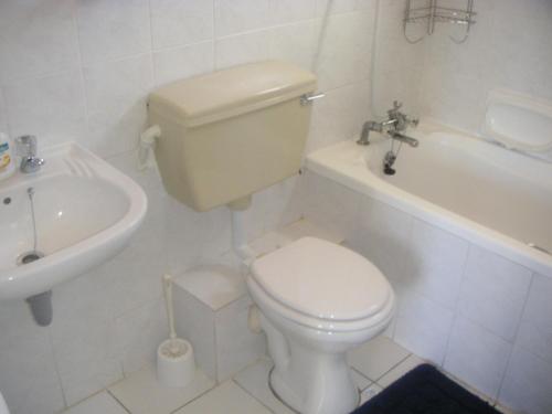 a white bathroom with a toilet and a sink at Waterside Living CL16 in Jeffreys Bay