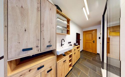 una cocina con armarios de madera y fregadero en Ferienhaus Hennewinkl en Oetz