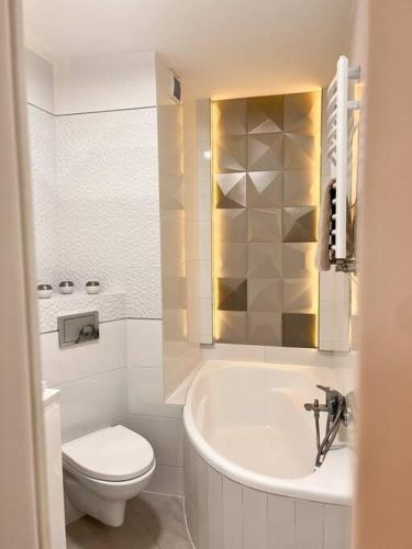 a bathroom with a toilet and a tub and a sink at Apartament Zamojski Młyńska in Zamość