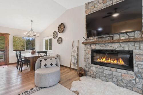 a living room with a stone fireplace with a tv at Open Sky Retreat - Close to Trails, Private Hot Tub, Big Yard, & Kid Friendly in Whitefish