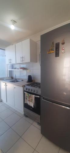 uma cozinha com um fogão de aço inoxidável e armários brancos em Linda y acogedora casa en Coquimbo em Coquimbo
