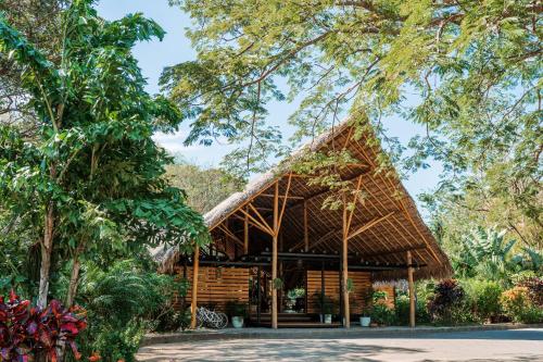 a pavilion with a thatched roof in a garden at TreeCasa Hotel & Resort Nicaragua in San Juan del Sur