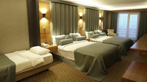 Una habitación de hotel con tres camas y una ventana. en Green Prusa Hotel, en Bursa
