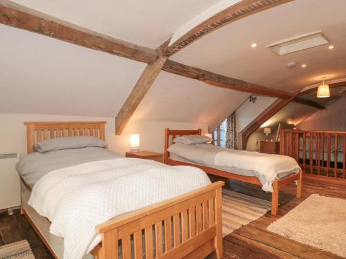 2 bedden in een zolderslaapkamer met houten balken bij Wards Court 2 in Gloucester