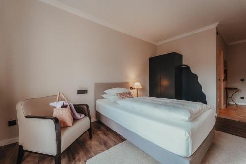 a bedroom with a large white bed and a chair at Hotel Villa Toskana in Leimen