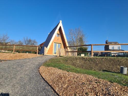 une petite maison avec un toit de chaume sur une route dans l'établissement Tiny House Ardennes, à Fromelennes