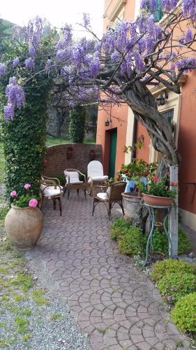 a patio with purple flowers and chairs and a tree at Villa Storica Calderino in Monte San Pietro