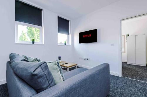 a living room with a couch and a tv on the wall at Spacious One-Bedroom Apartment in Saint Helens in Saint Helens