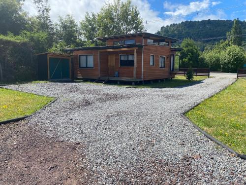 a home on a gravel driveway with a house at Cabañas M&R Lago Ranco in Lago Ranco