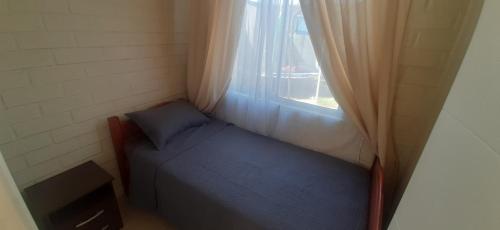 a small bedroom with a bed and a window at Linda y acogedora casa en Coquimbo in Coquimbo