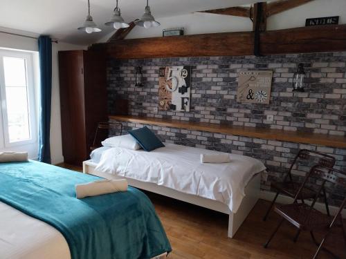 1 dormitorio con 2 camas y pared de ladrillo en La Maison des Maîtres de Forge en Moloy
