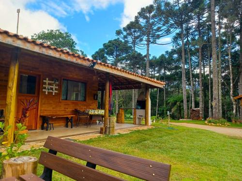 a wooden house with a bench in front of it at Sopro da Serra Chalés in Gonçalves
