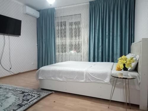 Квартиры Уют в Туркестане في Türkistan: غرفة نوم بسرير وطاولة مع ورد