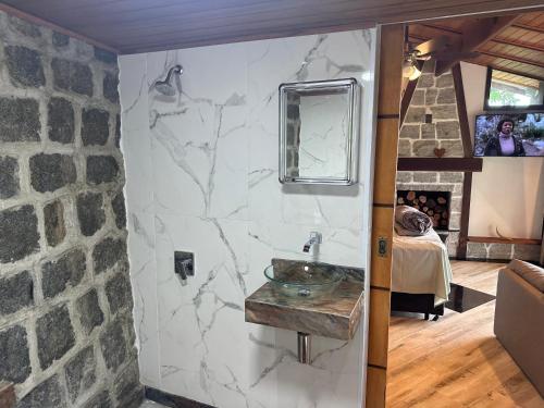 baño con pared de piedra y lavabo en Minas Em Marambaia en Río de Janeiro