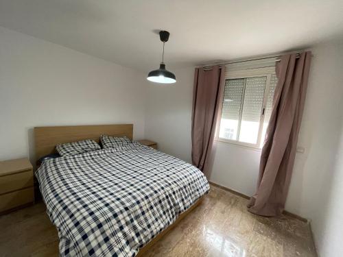 um quarto com uma cama com um cobertor xadrez e uma janela em Cosy & spacious apartment em Temara