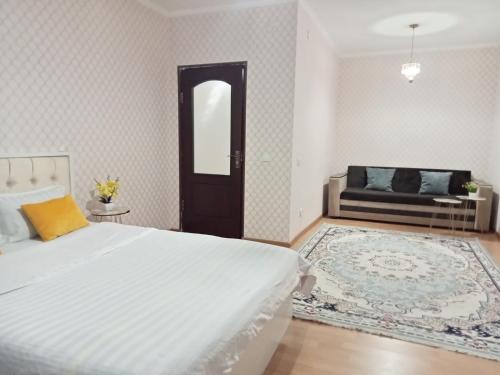 Квартиры Уют в Туркестане في Türkistan: غرفة نوم بسرير ومرآة وأريكة