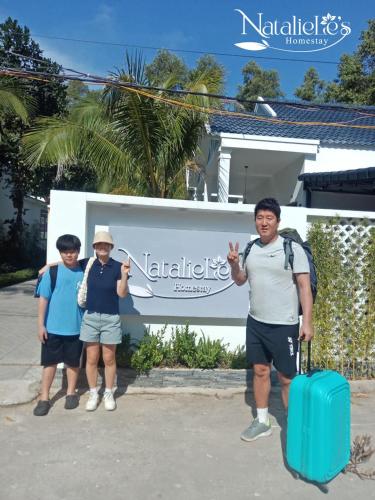 three people standing in front of a building with a suitcase at NatalieLe's Homestay in Phu Quoc