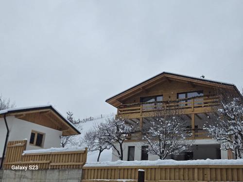 a large wooden house with a balcony in the snow at Casa Mara Viseu de Sus in Vişeu de Sus
