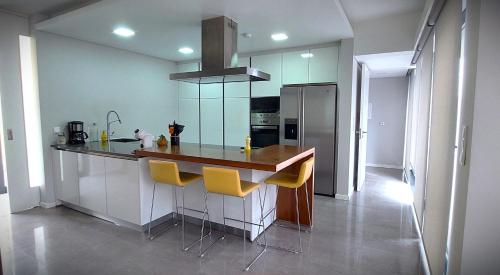 a kitchen with a counter with yellow bar stools at Casa Azul Terceira Island Azores in Fonte Bastardo