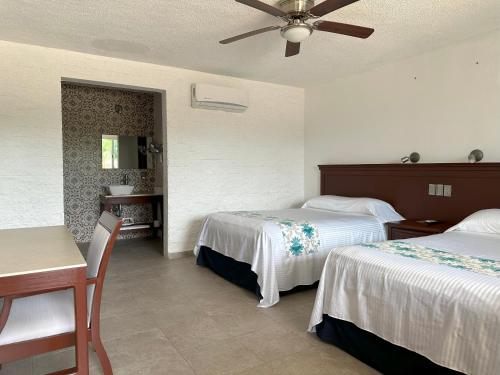 een hotelkamer met 2 bedden en een tafel bij Hotel Puerta Chichen in Chichén-Itzá