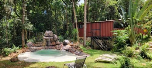 a garden with a small pool with a stone fountain at Econtainer Suítes Macacos in Macacos
