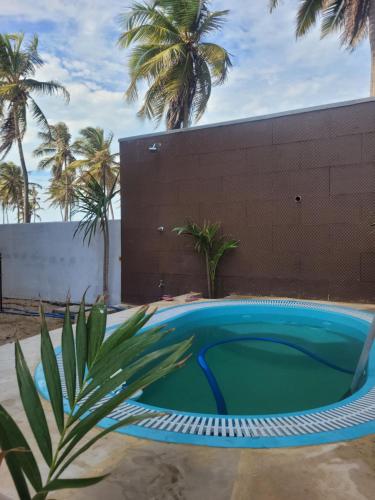 una pequeña piscina con palmeras en el fondo en FLECHEIRAS ATLANTICO en Trairi