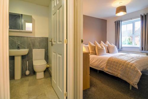 Charming 3 Bedroom, 2 Bathroom Home in Northampton - SKY TV included, Free Parking & WiFi by HP Accommodation في نورثامبتون: غرفة نوم بسرير ومغسلة ومرحاض