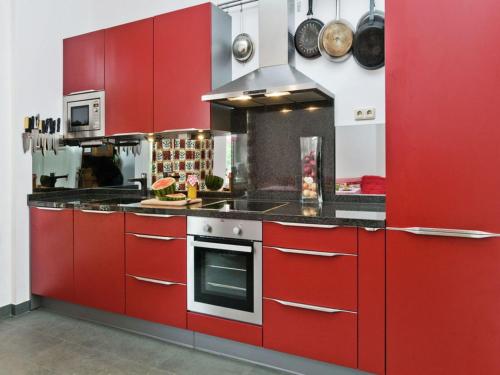 a large kitchen with red cabinets and appliances at Oude Pastorie en Dorpsschool Netze-Waldeck in Netze