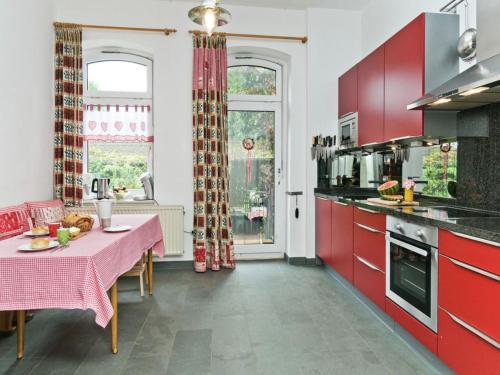 a kitchen with red cabinets and a table with a pink table cloth at Oude Pastorie en Dorpsschool Netze-Waldeck in Netze