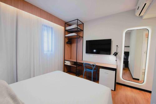a bedroom with a bed and a desk with a television at ibis Curitiba Shopping in Curitiba