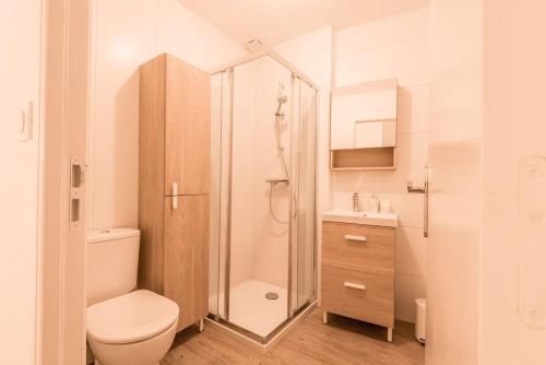 a white bathroom with a toilet and a shower at Le petit Lodge 
