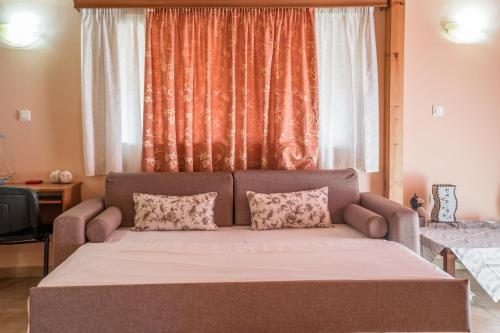 a couch with two pillows in front of a window at Belleza Villa in Lixouri