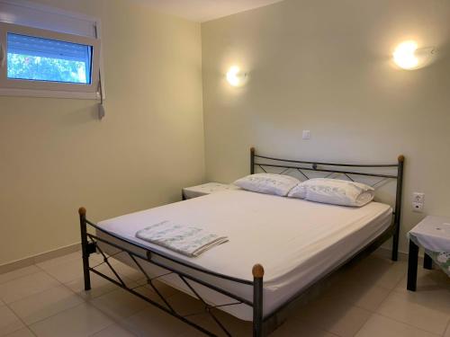 1 dormitorio con 1 cama con sábanas blancas y ventana en Sea melodies apartment 2, en Koroni