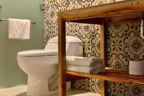 La salle de bains est pourvue de toilettes et de serviettes sur une étagère. dans l'établissement Hotel Puerta Chichen, à Chichén Itzá