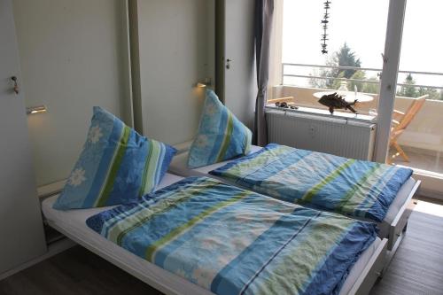 a bedroom with a bed with blue sheets and a window at Ferienwohnung-Meeresblick in Großenbrode