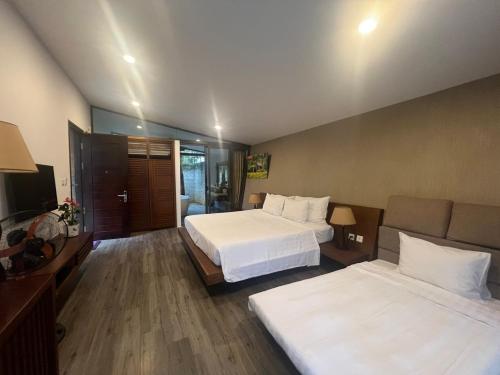 a hotel room with two beds and a television at Forest Villa at Dai Lai Resort in Ngọc Quang