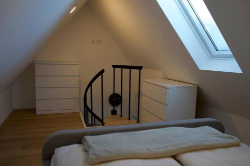 Cette chambre mansardée comprend un lit et un escalier. dans l'établissement Haus Allgäu Wohnung Schwabennestle, à Türkheim