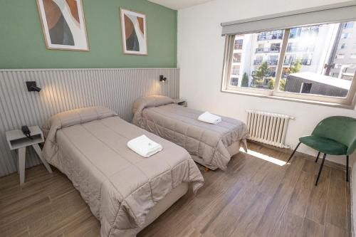 um quarto de hotel com duas camas e uma janela em M382 Hotel Bariloche em San Carlos de Bariloche