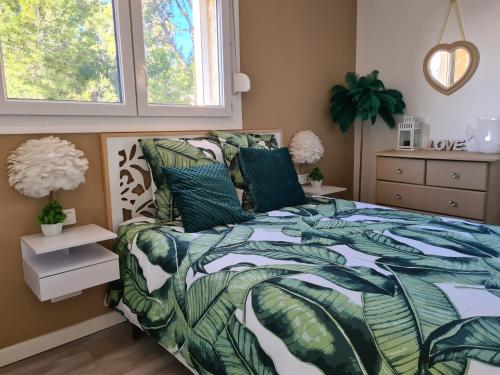 een slaapkamer met een bed met een groen en wit dekbed bij Petit coin de paradis les pieds dans l’eau in La Londe-les-Maures