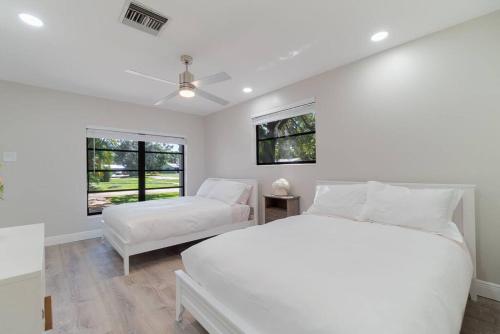 1 dormitorio blanco con 2 camas y ventana en Florida's finest living!, en North Palm Beach