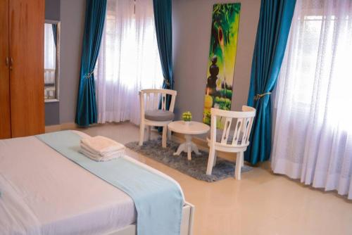 a bedroom with a bed and two chairs and a table at The Hidden gem Near Acacia Mall, 2 BDRs in Kampala