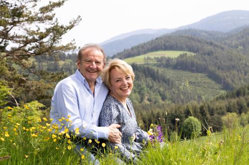 a man and a woman sitting in a field of flowers at André et Viviane Chatelard - Chambres d'hôtes in Saint-Bonnet-le-Froid