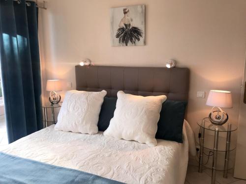 une chambre avec un lit avec des draps blancs et des oreillers dans l'établissement Appartement moderne à Fréjus - 39 m² - Vue sur mer, à Fréjus