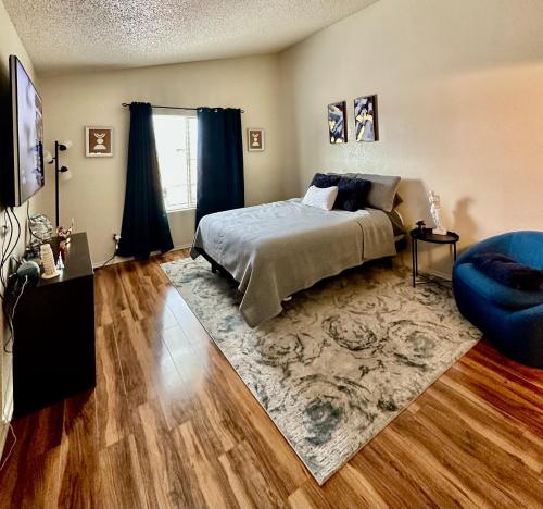 um quarto com uma cama e uma cadeira azul em Cozy remodeled-condo near TUC Airport & Downtown em Tucson