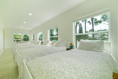 two beds in a white room with two windows at The Retreat #8231 in West Palm Beach